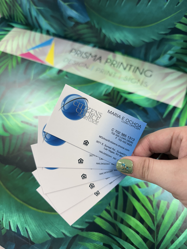 Custom business cards printed same day, held in front of shop sign